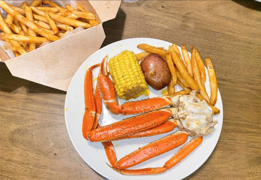 A plate of snow crab legs, a potato, and corn on the side, with cajun fries from Pier 88 Boiling Seafood & Bar in Las Vegas, Nevada