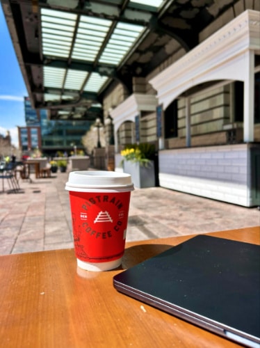 A red beverage cup of Pigtrain Coffee Co on an outdoor table