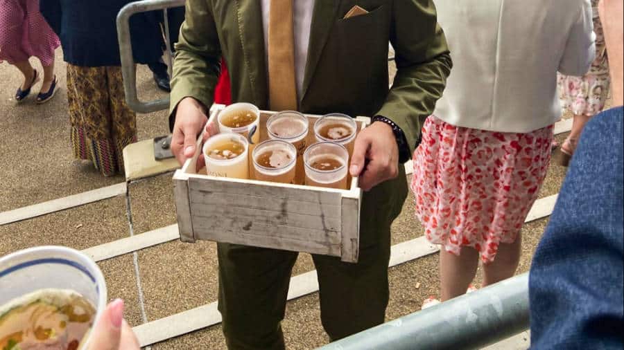 A man holding a crate with glasses of Pimm’s & lemonade