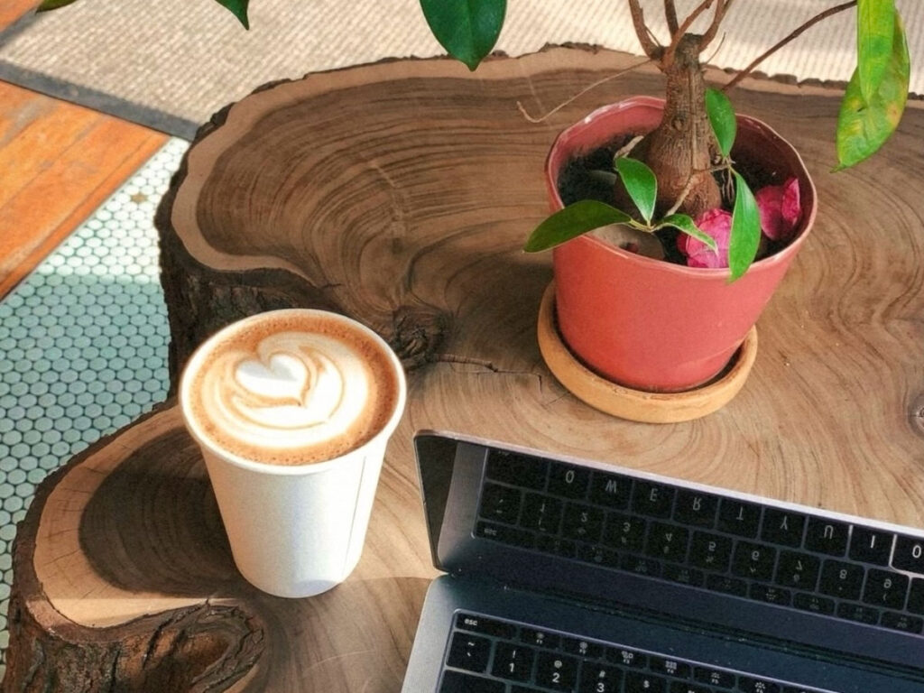 Coffee beside a laptop at Pinhole Coffee