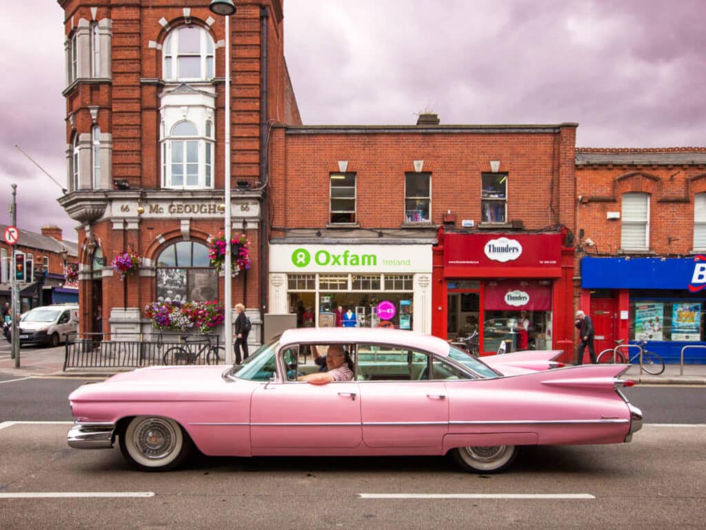 A pink Cadillac driving through the street of Phibsborough