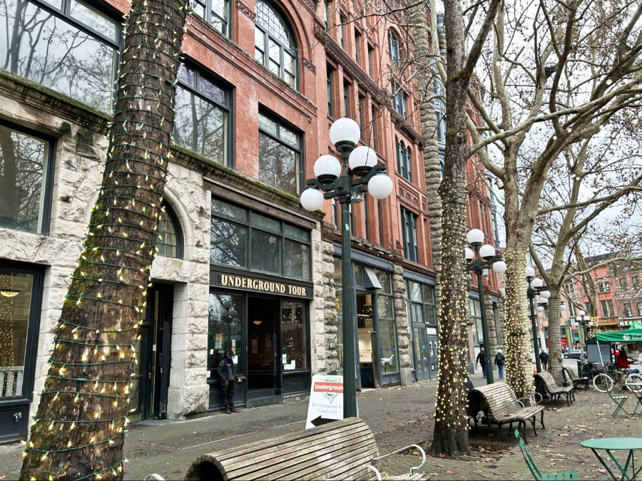 Exterior view of the Underground Tour in Pioneer Square with benches and stringed lights around the trees
