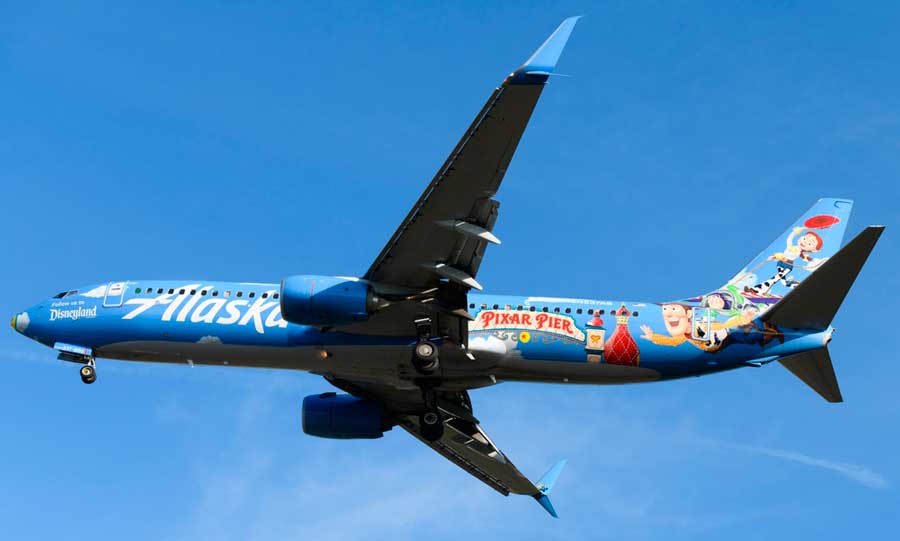 An airplane painted with Pixar Pier up in the clear blue sky