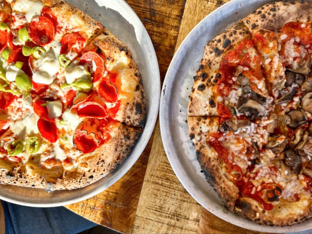 Closeup view of the two variety of pizza from Crosscut Pizzeria and Taphouse