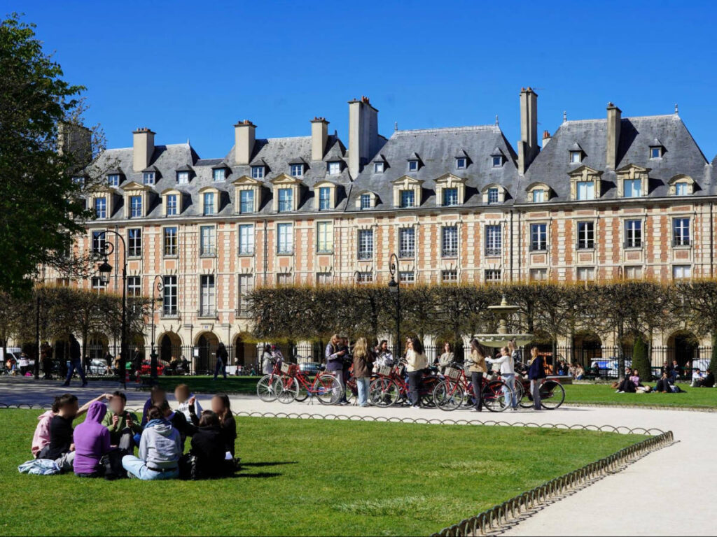 Clear blue sky over the people and the Place des Vosges park