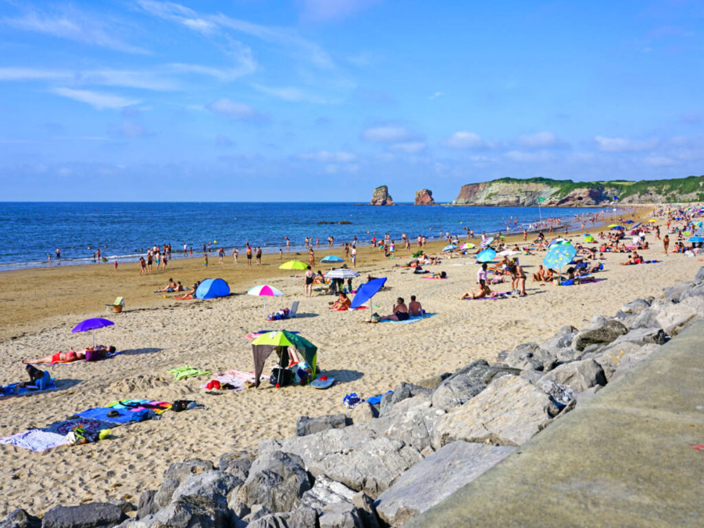 The people enjoying the sunny day along the shoreline of Plage d’Hendaye
