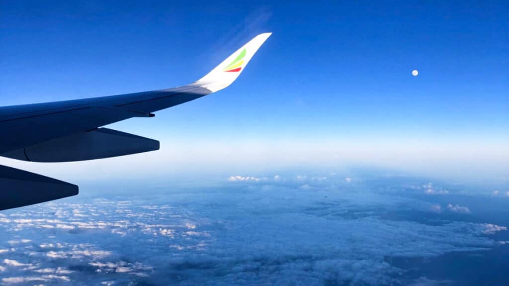 View of the plane's wing from the window seat with the moon in the background
