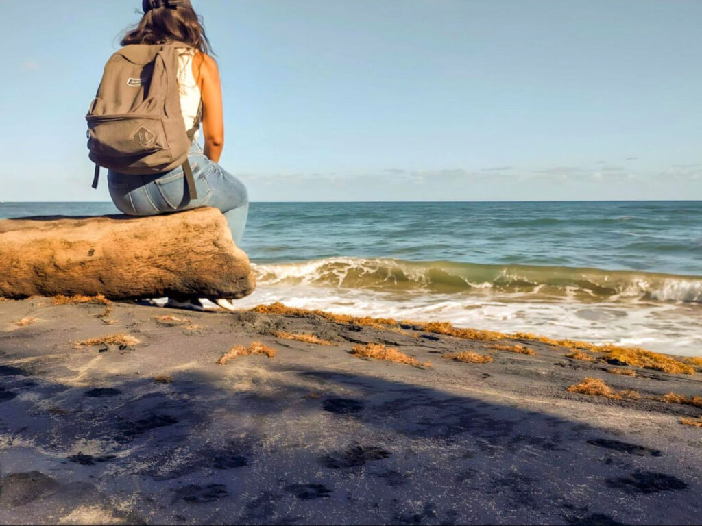Author Vanessa Ramos sitting in a fallen tree admiring Playa Los Bohios