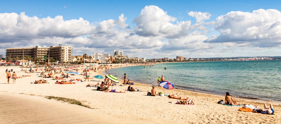 People enjoying the sun along the coastline of Platja de Palma beach