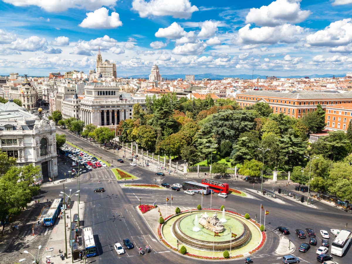 Aerial view of Plaza de Cibeles with lush trees around and the blue sky in the background