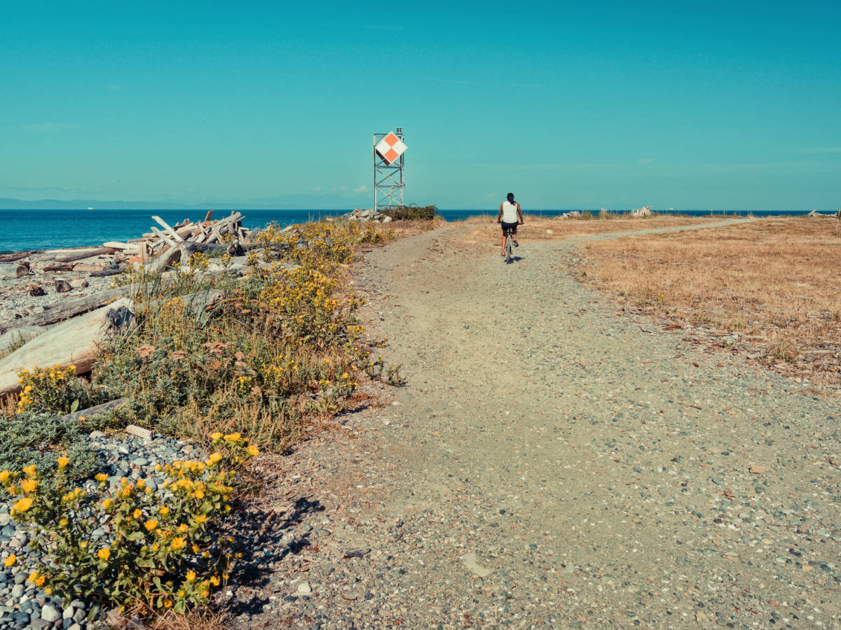 A woman biking under the clear blue sky in Point Roberts