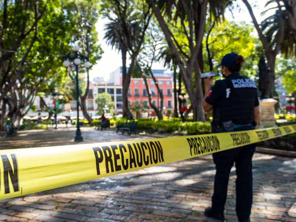 Back view of a Policewoman making a call with caution tape in front