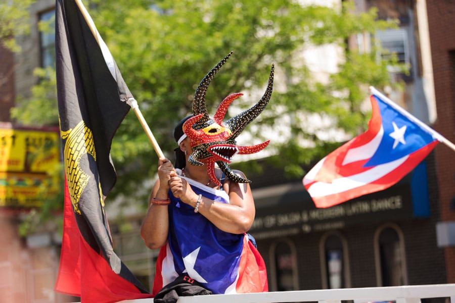 A woman wearing a traditional mask from Puerto Rico during a parade