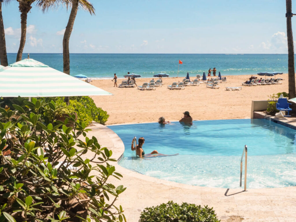 View of the people swimming on the pool overlooking the beach at La Concha Renaissance San Juan Resort