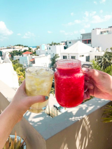 Hands holding poolside drinks and a view on the background