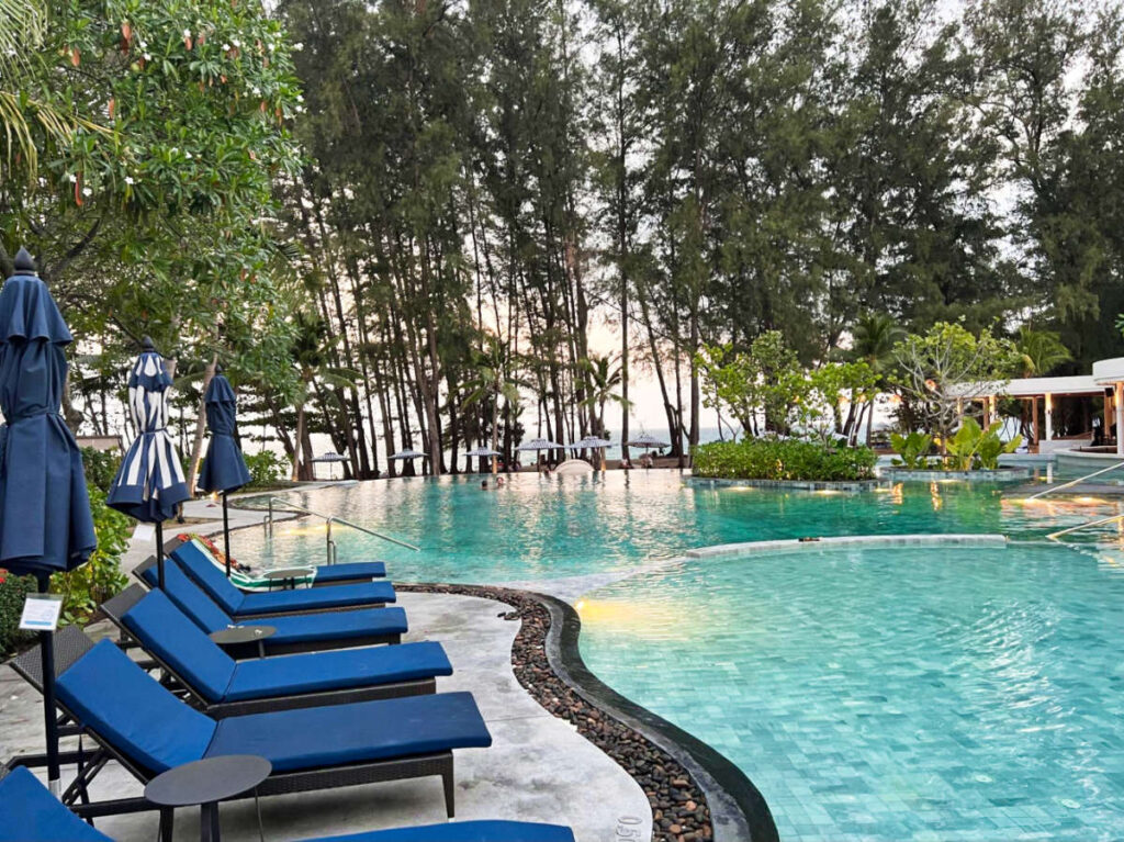 The pool area surrounded by lounge chairs and greenery at Le Méridien Phuket Mai Khao