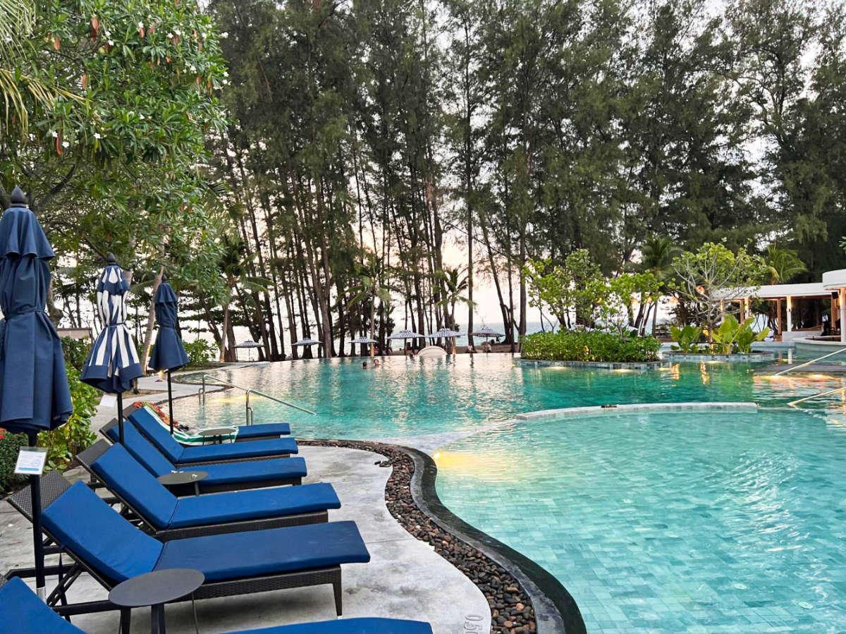 The pool area surrounded by lounge chairs and greenery at Le Méridien Phuket Mai Khao