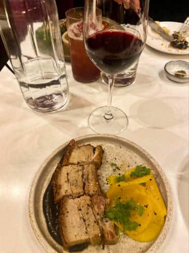 A plate of pork belly and a glass of wine from Ottolenghi