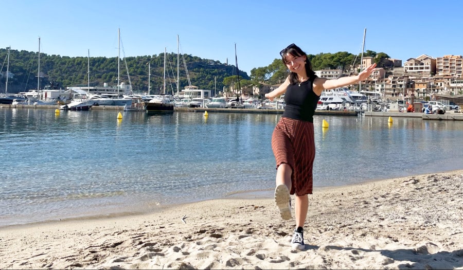 The author Lea Rose Allbaugh posing near the Port de Soller with boats docked around