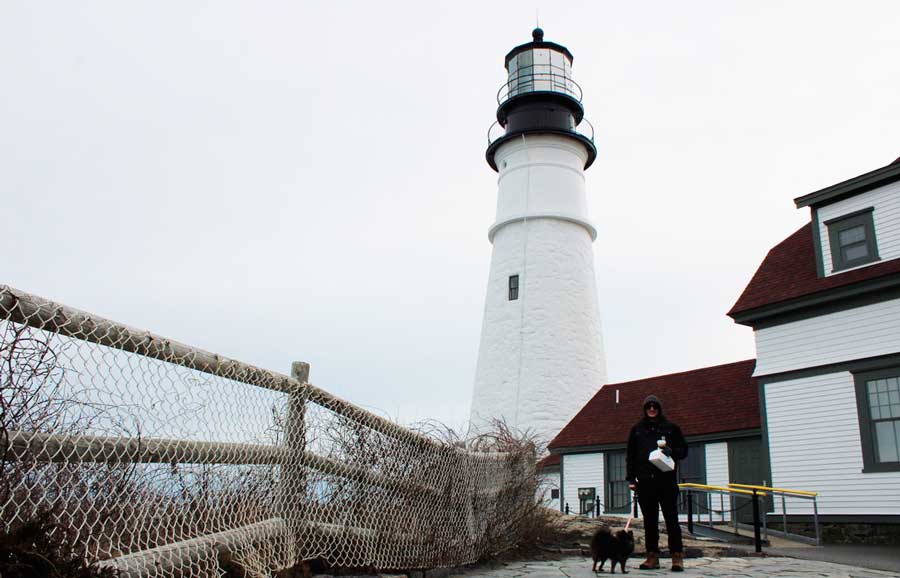 A man with his dog in front of the Portland Head Light