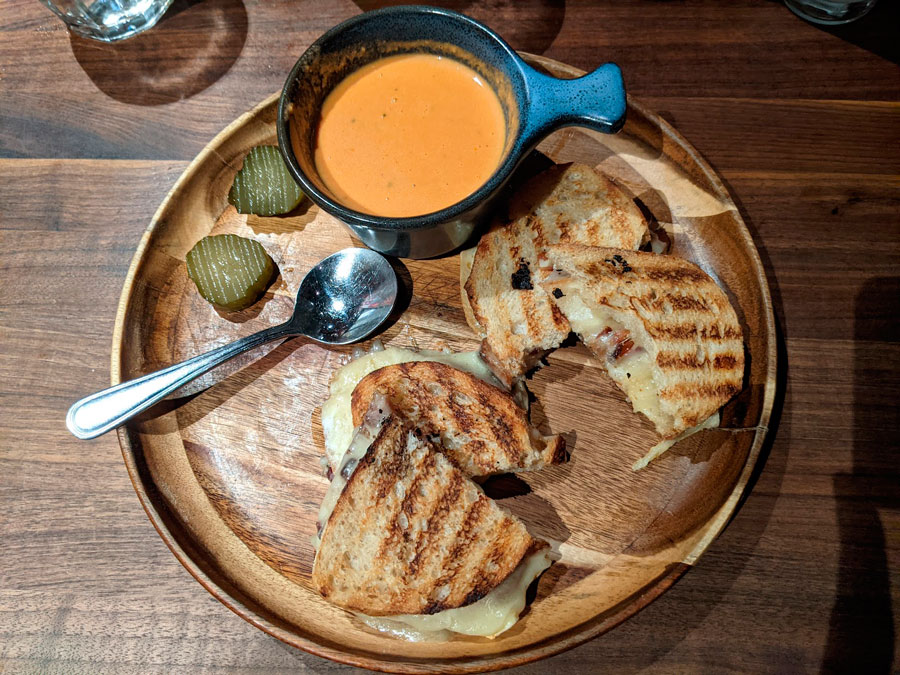 The OMG Grilled Cheese with dip on a wooden plate in Postino