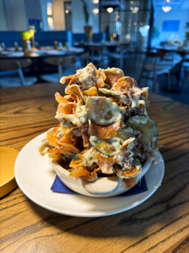 A tower of potato and zucchini chips on a small plate from Luogo