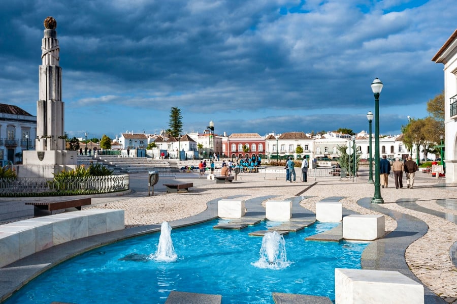 View of the beautiful fountain and people walking around the Town Square Praca da Republica in Tavira