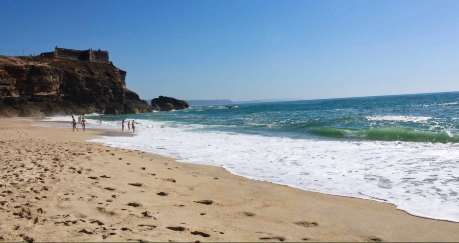 Tourists playing the waves at the shore of Praia do Norte