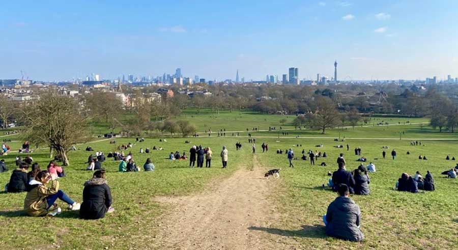 People sitting at the greenfield of Primrose Hill