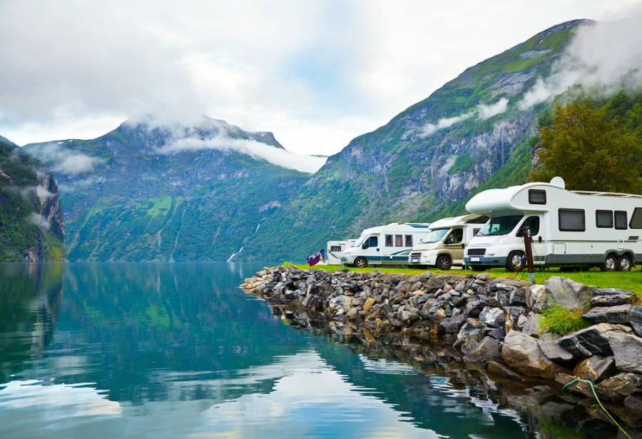 Camper vans at a campsite with a scenic view of the mountain and the lake in Geirangerfjord