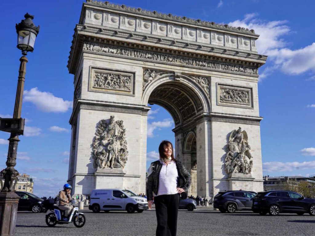 The author Rachel Kapelke-Dale posing for a photo in front of the  Arc de Triomphe