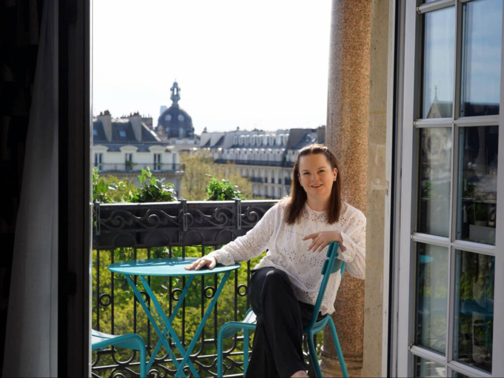 The author Rachel Kapelke-Dale sitting on a balcony of Solly Hôtel