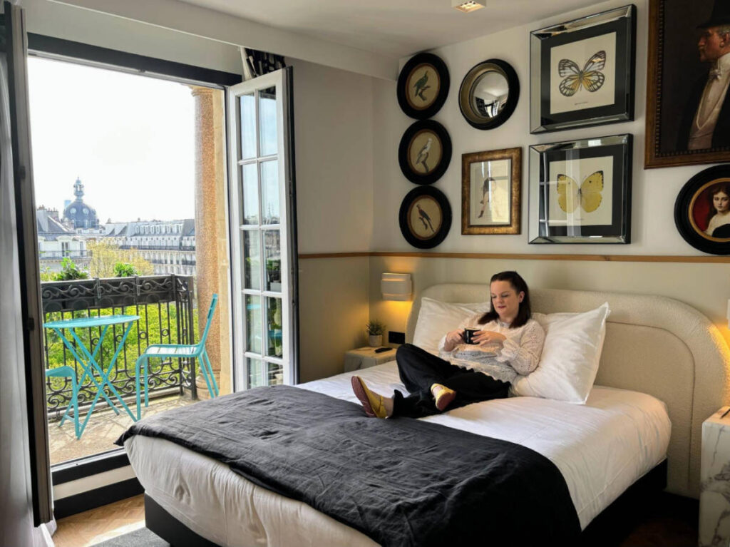 The author Rachel Kapelke-Dale sitting on her bed at the Solly Hôtel