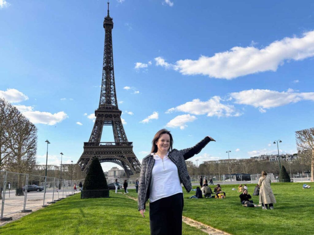 The author Rachel Kapelke-Dale posing for a photo in front of the Eiffel Tower