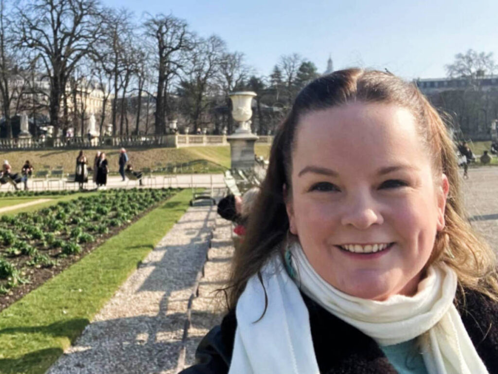 The author Rachel Kapelke-Dale smiling for a photo at the Luxembourg Gardens