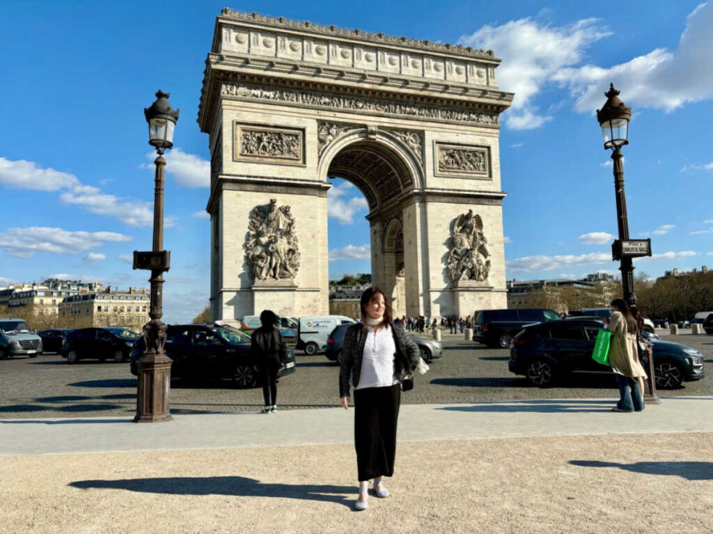 The author Rachel Kapelke-Dale posing for a photo in front of the Arc de Triomphe