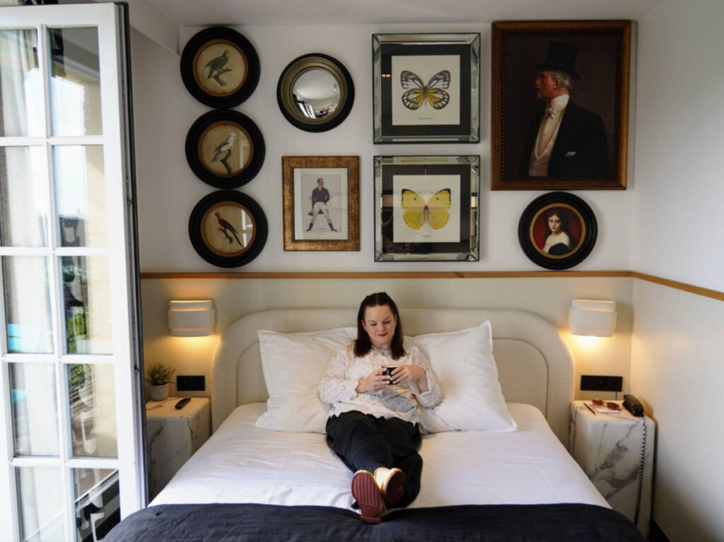 Travel Lemming writer Rachel on the hotel bed with a gallery wall in the background
