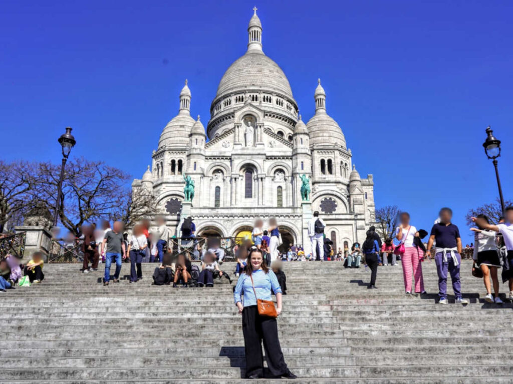 The author Rachel Kapelke-Dale posing for a photo on the steps of Sacré Coeur Basilica