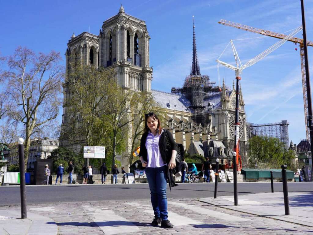 The author Rachel Kapelke-Dale posing for a photo outside with the Notre Dame Cathedral in the background