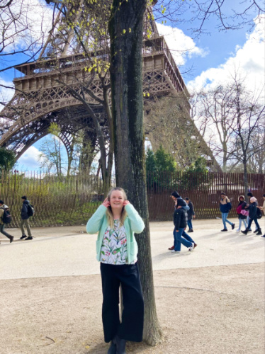 The author Rachel smiling for a photo with the Eiffel Tower in the background