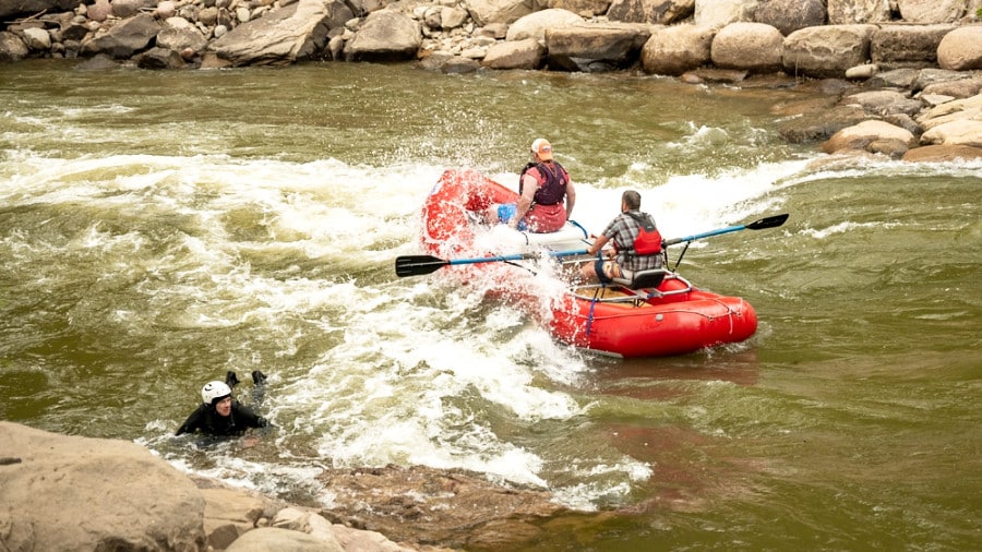 Tourists enjoying the water rafting on a red boat and swimming at the Animas River