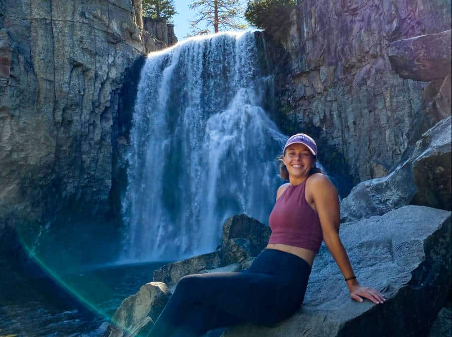 The author (Ashleigh Bandimere) sitting on a big stone at the base of the Rainbow Falls in Mammoth Lakes