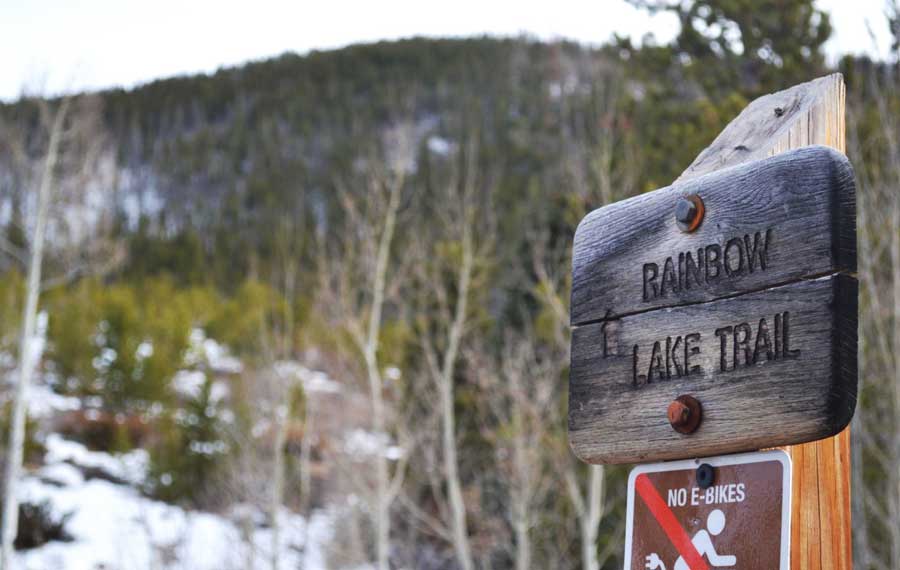 The Rainbow Lake Trail sign and a No E-bike warning sign