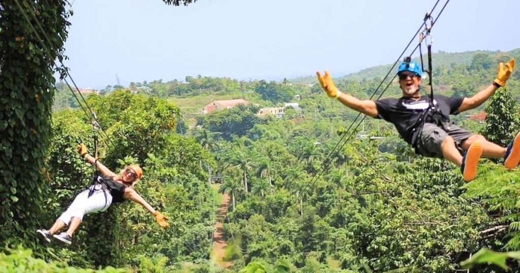 A couple ziplining over the lush rainforest on a sunny day