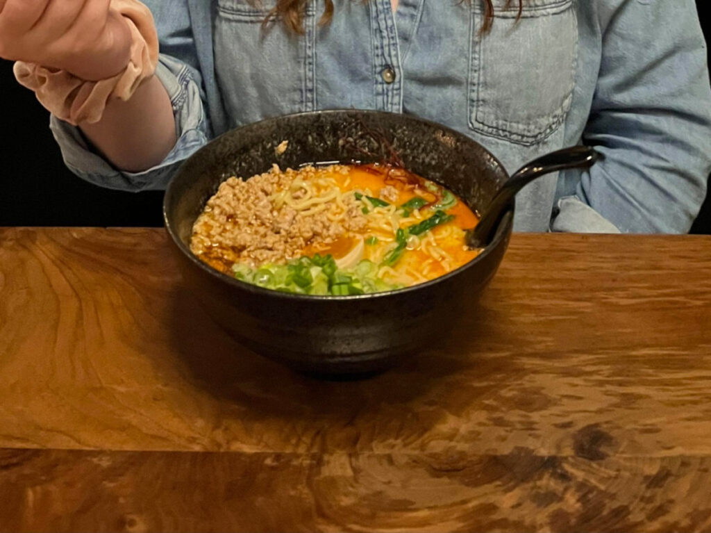 Author Elizabeth Demolat eating a ramen from Two Ten Jack 
