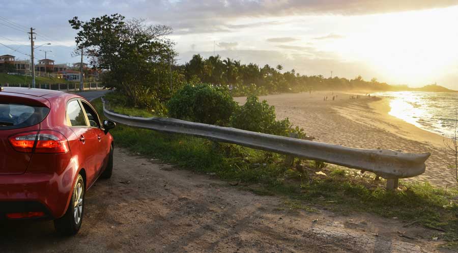 View of a red car with an overlooking view of the beach
