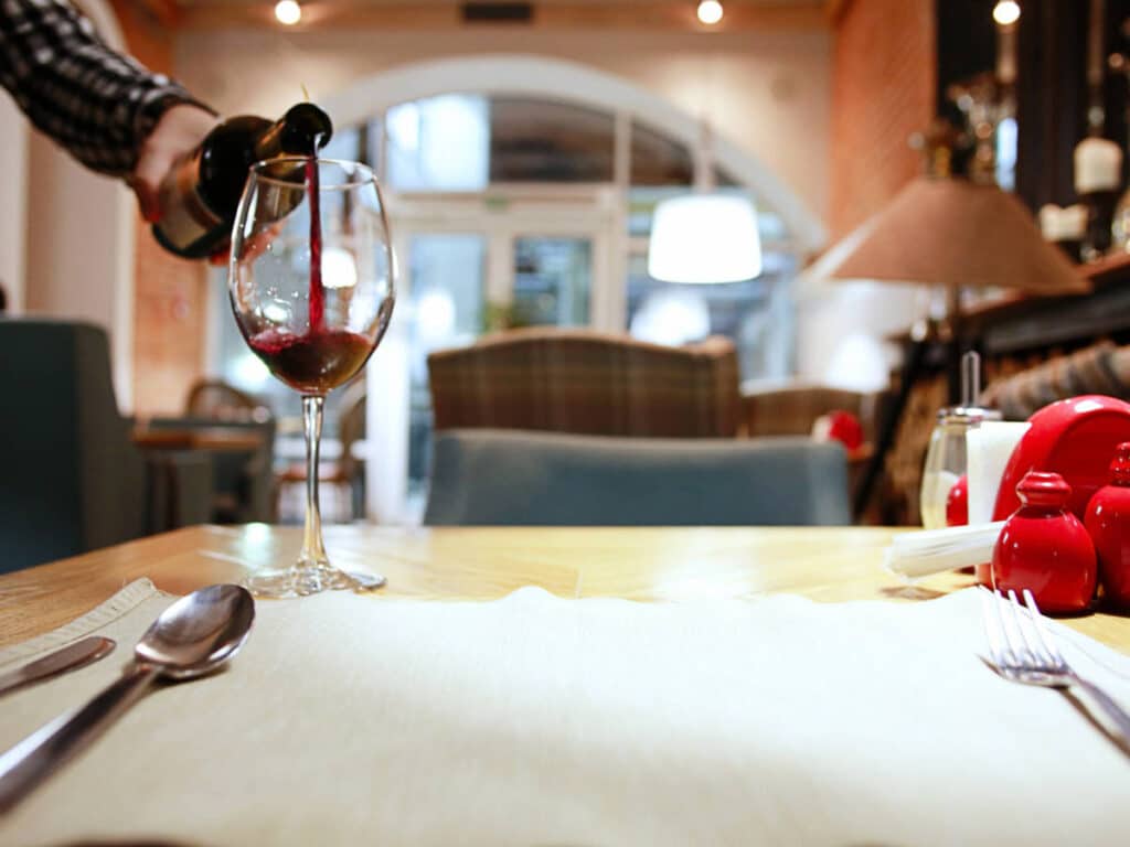 A server pouring a red wine on a glass wine at Granite