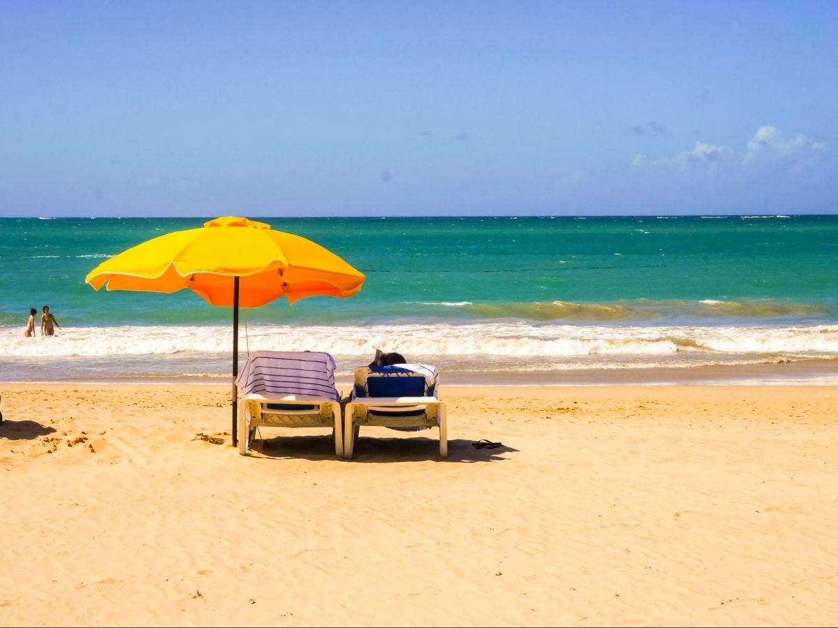 Two beach chairs and a yellow umbrella at Isla Verde Beach