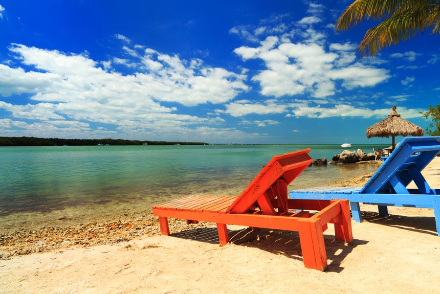 View of two wooden beach chairs along the shoreline of Florida Keys