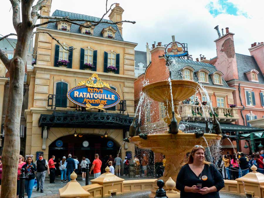 View of people outside the Remy’s Ratatouille Adventure and a water fountain in front of it